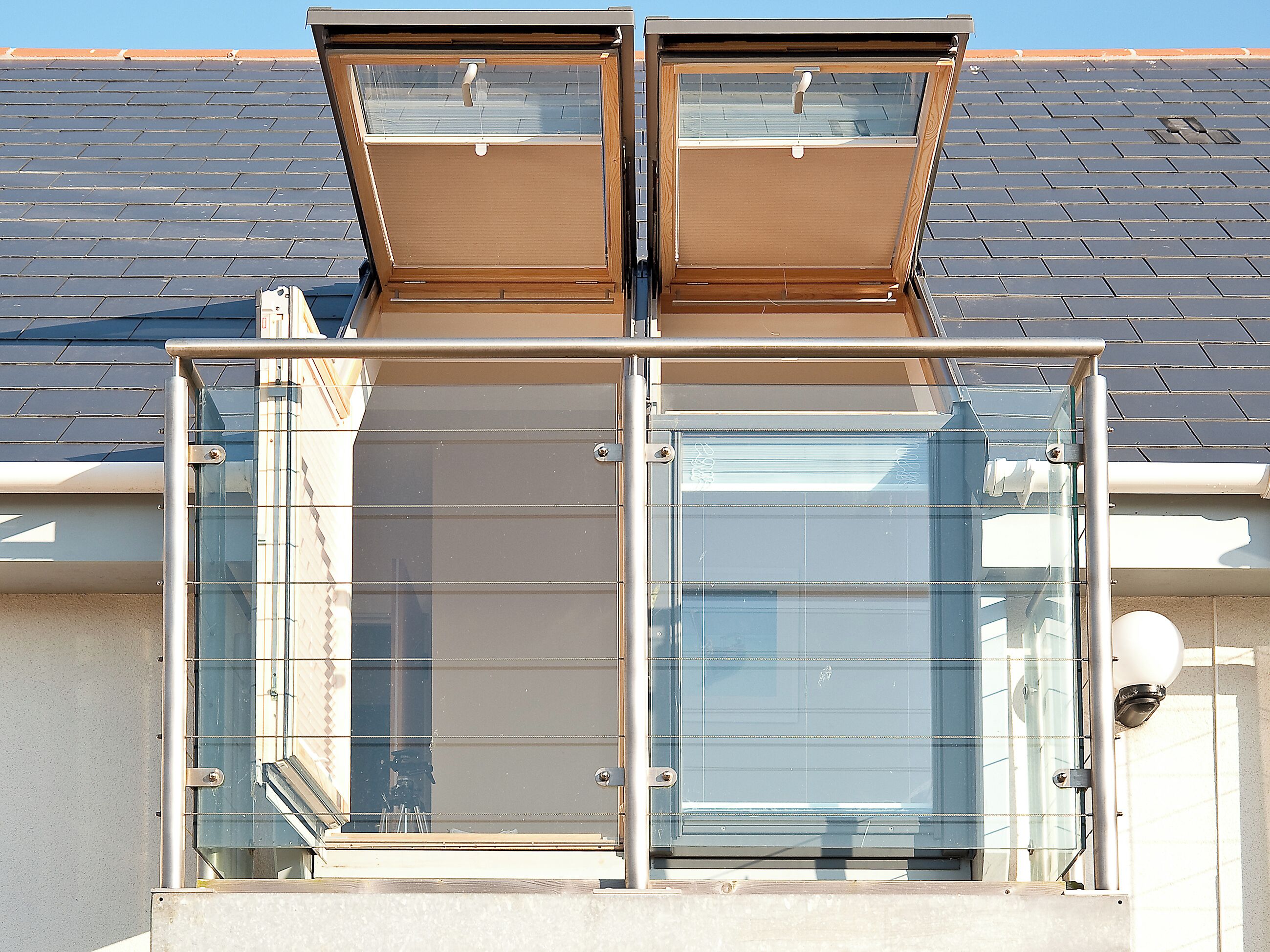 A modern building with a glass balcony and a metal railing.