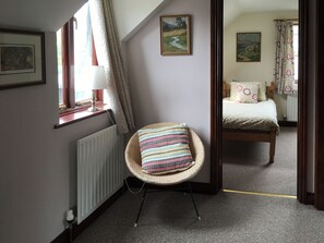 A room with a wicker chair, a bed, a radiator, and a window with curtains. - 3 bedroom accommodation in Near Ely (Near Ely)