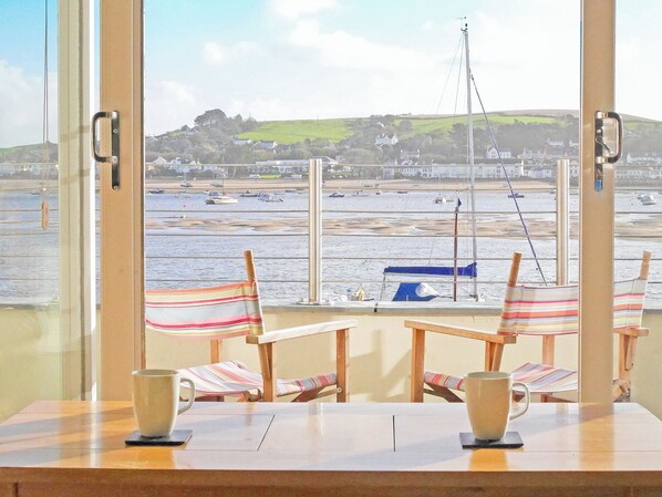 A room with a large window overlooking a beach, two striped chairs, and two mugs on a table. - 3 bedroom accommodation in Appledore, near Bideford (Appledore, near Bideford)