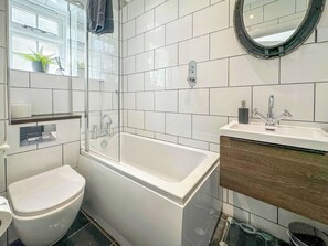 A modern bathroom with a toilet, a glass-enclosed shower, a bathtub, a sink with a wooden vanity, and a mirror. - 3 bedroom accommodation in Appledore, near Bideford (Appledore, near Bideford)