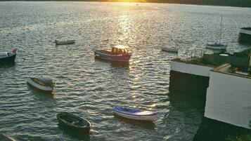 A marina with several boats docked, a building with a white exterior, and a sunset in the background.