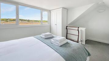 A bedroom with a bed, a window with a view, a radiator, and a towel rack.