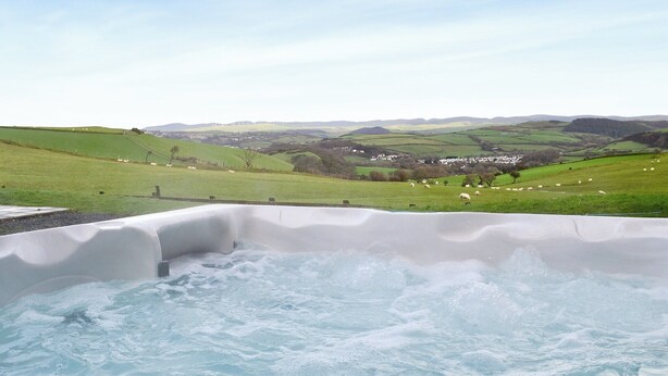 Un jacuzzi con vistas a un valle verde y colinas.