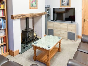 A cozy living room with a fireplace, a television, a bookshelf, and a coffee table. - 3 Catherine Cottages (Keswick)