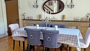 A dining area with a wooden herringbone floor, a stone fireplace, and a mirror above the table. - Bryn Euryn Cottage - 28135 (Rhos-on-Sea, near Colwyn Bay)