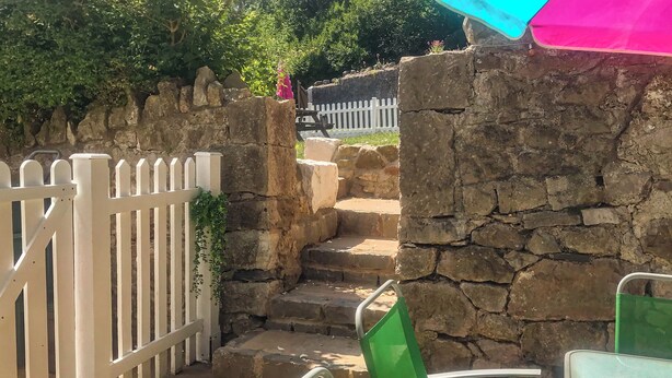 A stone staircase leading up to a white picket fence, with green chairs and a table in the foreground. - Bryn Euryn Cottage - 28135 (Rhos-on-Sea, near Colwyn Bay)