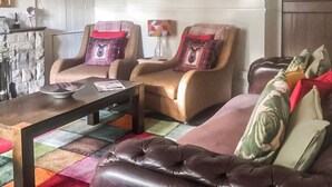A living room with a brown leather sofa, two armchairs, a coffee table, and a colorful rug. - Bryn Euryn Cottage - 28135 (Rhos-on-Sea, near Colwyn Bay)