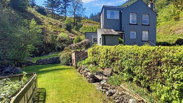 A two-story house with a stone wall and a wooden bench in the yard. - 2 bedroom accommodation in Seldom Seen near Thornthwaite (Seldom Seen near Thornthwaite)