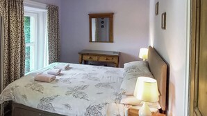 A bedroom with a bed, a nightstand, a lamp, and a mirror. - 2 bedroom accommodation in Seldom Seen near Thornthwaite (Seldom Seen near Thornthwaite)