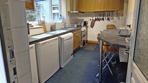 A compact kitchen with wooden cabinets, a built-in dishwasher, a stove, and a small dining area. - 2 bedroom accommodation in Seldom Seen near Thornthwaite (Seldom Seen near Thornthwaite)