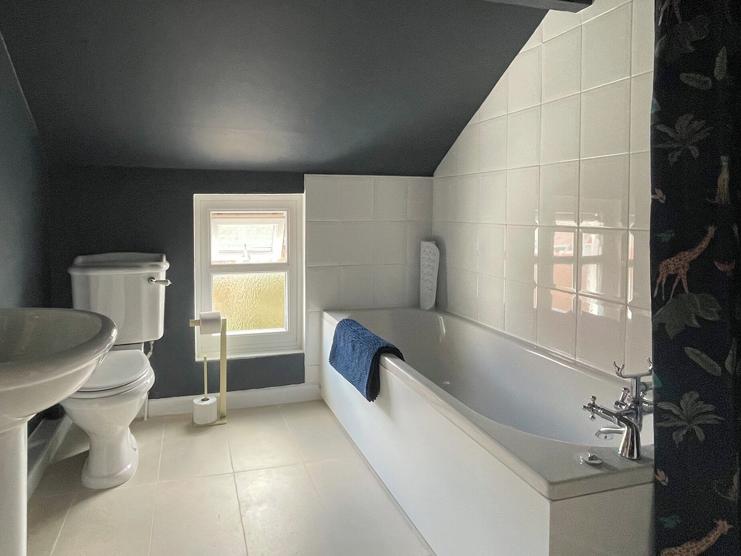 Een badkamer met toilet, wastafel, bad en een raam.