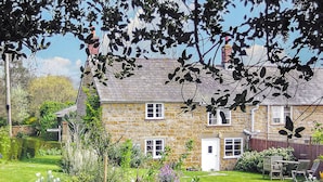 A stone house with a well-maintained garden, a visible door, and a chimney. - 2 bedroom accommodation in North Chideock, near Bridport (North Chideock, near Bridport)