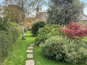A garden with a stone pathway leading to a house. - 2 bedroom accommodation in North Chideock, near Bridport (North Chideock, near Bridport)