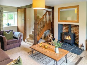Una sala de estar acogedora con chimenea, una escalera de madera y un sofá cómodo.