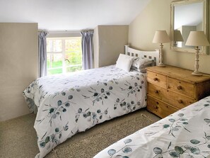 A bedroom with a bed, a dresser, a mirror, and a window with curtains.