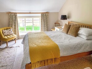 A bedroom with a large bed, a chair, a nightstand, and a lamp.