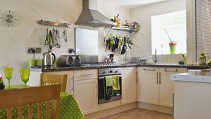 Cozinha com fogão, forno e diversos utensílios pendurados na parede.