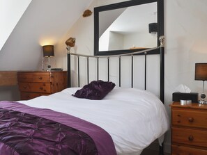 A bedroom with a bed, a dresser, a mirror, and a lamp.