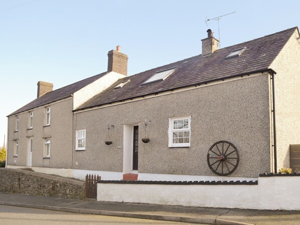 A two-story house with a white exterior, a chimney, and a wheel well on the side.
