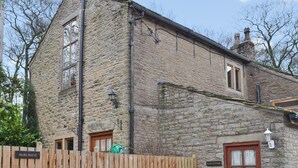 Una cabaña de piedra con valla de madera, puerta de madera y un letrero que dice "MARL HOUSE".