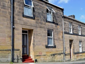A two-story stone building with a red door and white-framed windows. - A period cottage within a short walk of Alnwick town centre. (Alnwick)