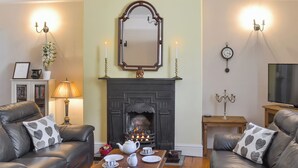 A living room with two leather sofas, a wooden coffee table with tea set, a fireplace, and wall-mounted lighting.