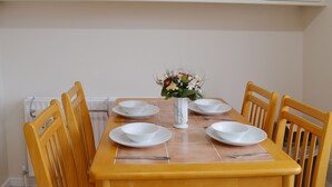 A dining table set with white plates, bowls, and a vase with flowers. - 2 bedroom accommodation in Hopton-on-Sea, near Great Yarmouth (Hopton-on-Sea, near Great Yarmouth)