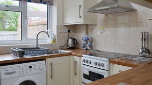 A compact kitchen with a washing machine, a stove, and a sink. - 2 bedroom accommodation in Hopton-on-Sea, near Great Yarmouth (Hopton-on-Sea, near Great Yarmouth)