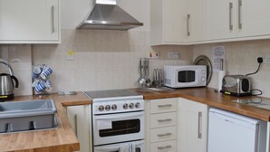 A kitchen with white cabinets, a stainless steel range hood, a microwave, a toaster, and a kettle. - 2 bedroom accommodation in Hopton-on-Sea, near Great Yarmouth (Hopton-on-Sea, near Great Yarmouth)