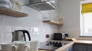 Una cucina moderna con piastrelle bianche, elettrodomestici in acciaio inossidabile e piani di lavoro in legno.