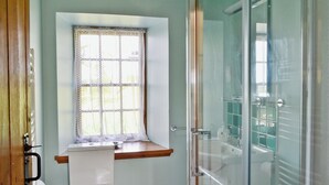 A bathroom with a toilet, a window with a curtain, and a glass shower enclosure. - 4 bedroom accommodation in Bayfield, Nigg (Bayfield, Nigg)
