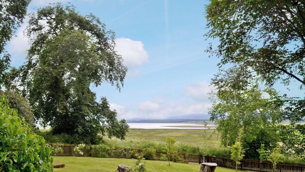 A well-maintained garden with a lawn, a wooden fence, and a stone table. - 4 bedroom accommodation in Bayfield, Nigg (Bayfield, Nigg)