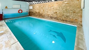 An indoor swimming pool with a stone wall and a lifebuoy. - 5 bedroom accommodation in Uploders, Bridport (Uploders, Bridport)