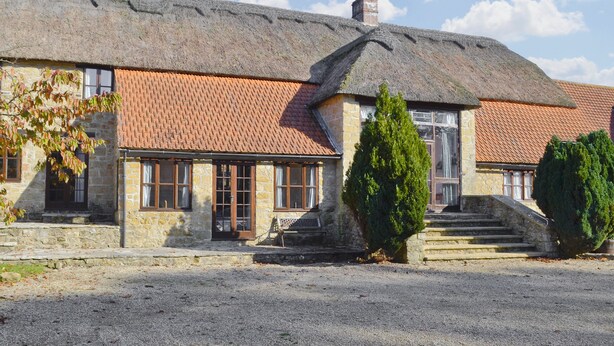 A stone building with a tiled roof, a staircase leading to the entrance, and a gravel driveway. - 5 bedroom accommodation in Uploders, Bridport (Uploders, Bridport)