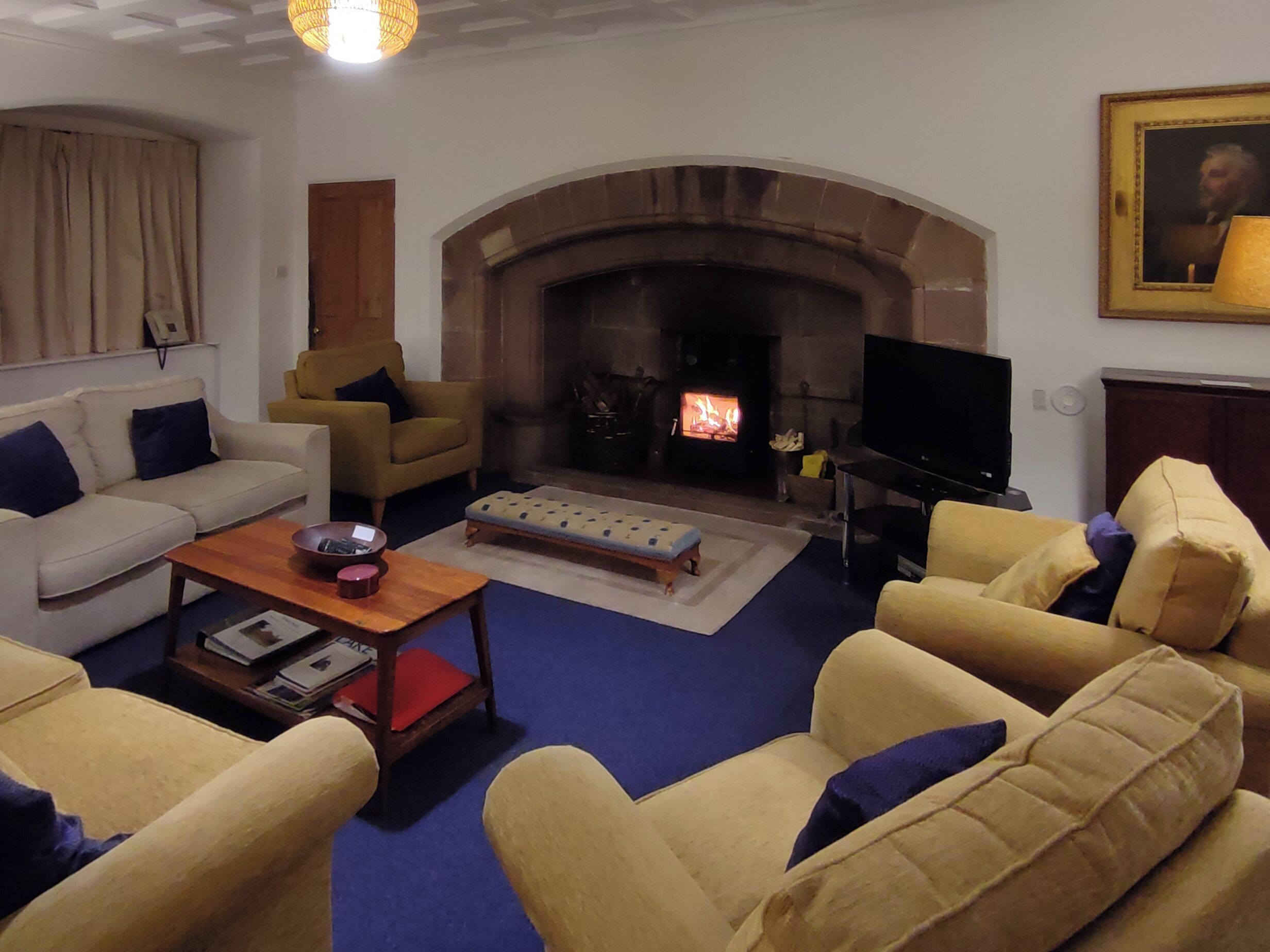 Una sala de estar con chimenea, sofás, un televisor y una estantería.