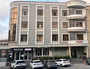 A hotel with a modern facade, a restaurant named 'Royal Restoran' at the ground level, and a parking area with several cars. - Royal Hotel (Baku)