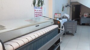 A large industrial machine, possibly a textile printer, in a room with tiled flooring and a white wall. - Royal Hotel (Baku)