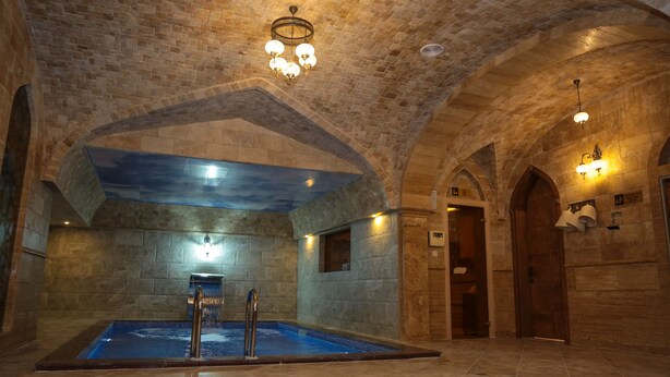 Zona d'spa amb paret de pedra, piscina i sostres voltes.