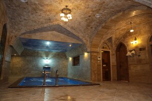 A spa area with a stone wall, a pool, and arched ceilings.
