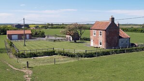 A rural property with a large brick house, a smaller attached building, and a fenced garden area. - Somer Leyton Cottage (Hogsthorpe, near Chapel St Leonards)