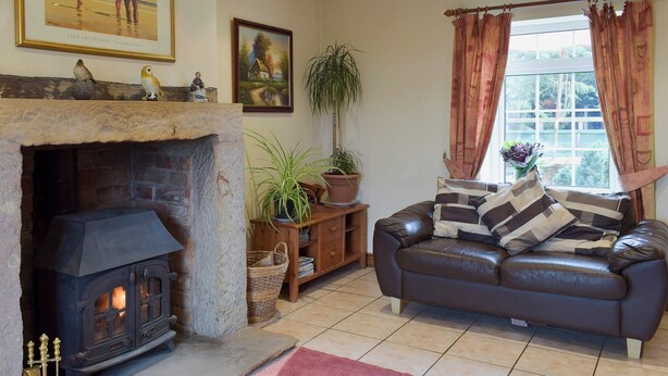 Un salón acogedor con chimenea de piedra, un sofá de cuero y un ventanal con cortinas.