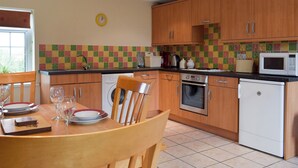 Una cocina con armarios de madera, microondas, tostadora y lavadora.