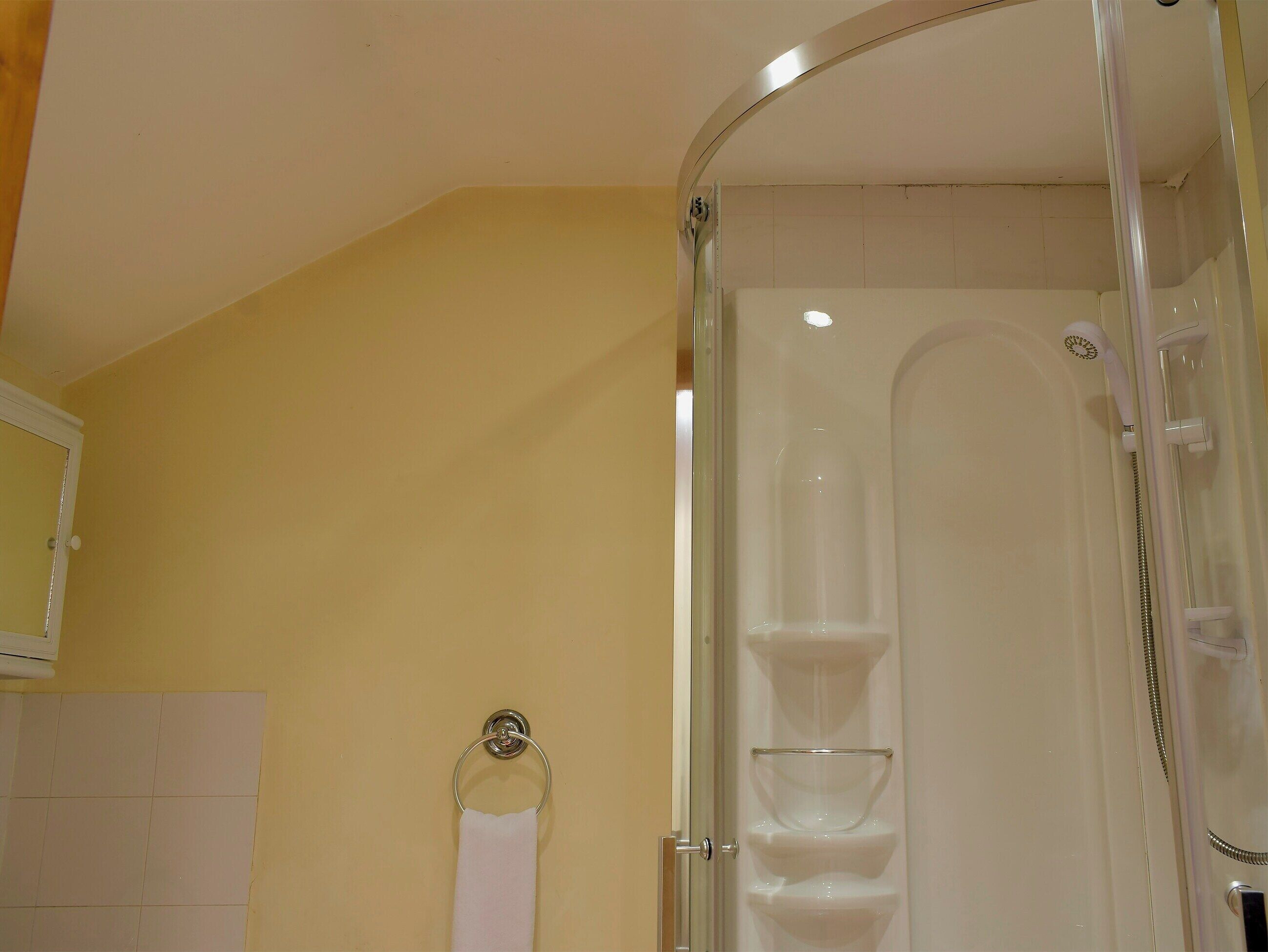 Ein Badezimmer mit einer gläsernen Duschkabine, einem weißen Handtuchhalter und einer gefliesten Wand.