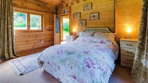 Een houten slaapkamer met een bed, nachtkastjes en een raam.