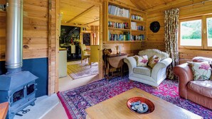 Een gezellig houten blokhutinterieur met een open haard, boekenkasten, een bank en een eethoek.