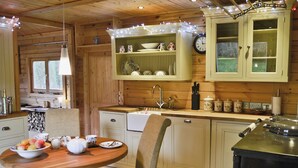 Een houten keuken in een vakantiehuis, met een eettafel, stoelen en een fornuis.