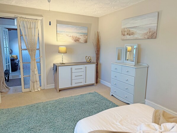 A bedroom with a bed, a dresser, a lamp, and a painting on the wall.