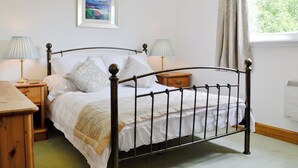 A neatly made bed with white linens and a wooden headboard. There are two bedside tables, each with a lamp and a small wooden nightstand. A framed picture hangs on the wall above the bed. - 2 bedroom accommodation in Clachan Seil, near Oban (Clachan Seil, near Oban)