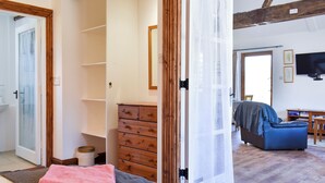 A room with a bed, a wooden dresser, a chair, and a television.