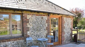 A rustic building with a stone facade, a wooden door, and a small patio area with a table and chairs.